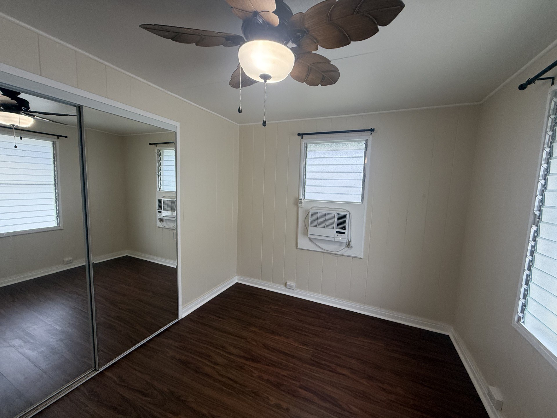 A room with a ceiling fan and a window with blinds.